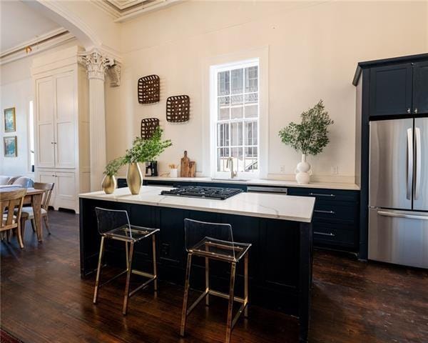 kitchen with a center island, dark hardwood / wood-style floors, a kitchen bar, black gas stovetop, and stainless steel refrigerator