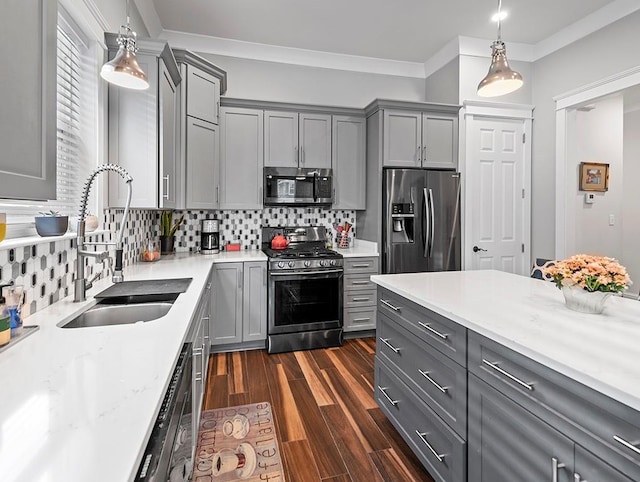 kitchen featuring pendant lighting, stainless steel appliances, gray cabinets, and sink