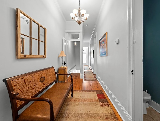 hall featuring ornamental molding, an inviting chandelier, and light hardwood / wood-style flooring