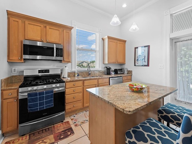 kitchen with light tile patterned flooring, sink, decorative light fixtures, stainless steel appliances, and a breakfast bar