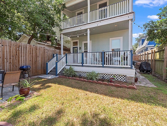 entrance to property with a balcony, a wooden deck, and a lawn