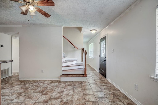 interior space featuring ornamental molding, ceiling fan, and a textured ceiling