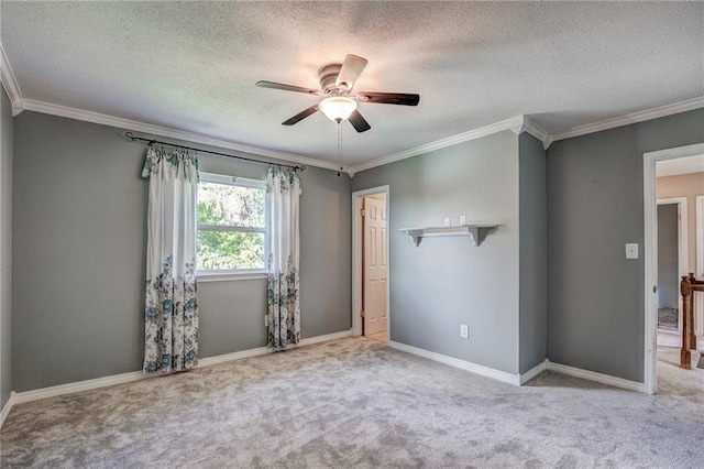 carpeted empty room featuring ceiling fan, a textured ceiling, and crown molding