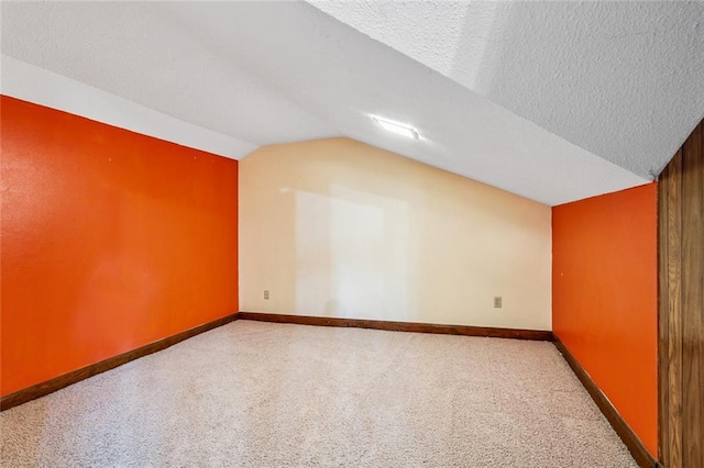 additional living space with carpet flooring, a textured ceiling, and vaulted ceiling