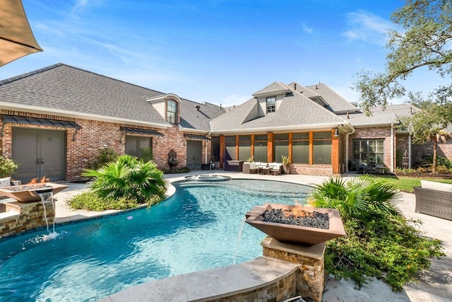 view of swimming pool with pool water feature, a patio, and an outdoor living space with a fire pit