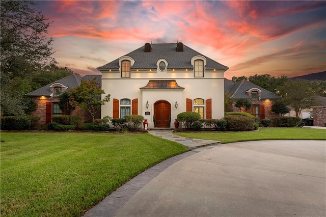 french country style house featuring a lawn