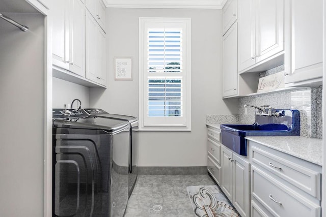 laundry area featuring sink, light tile patterned floors, cabinets, ornamental molding, and washing machine and clothes dryer