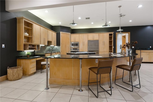 kitchen featuring light brown cabinetry, pendant lighting, stainless steel appliances, and a center island