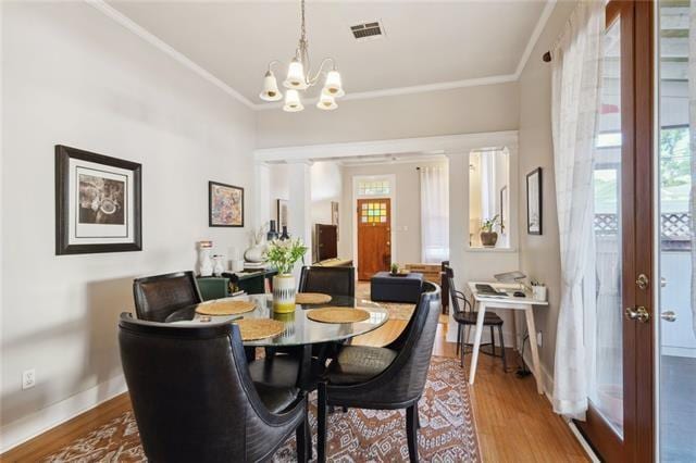 dining space with hardwood / wood-style flooring, a chandelier, ornamental molding, ornate columns, and french doors