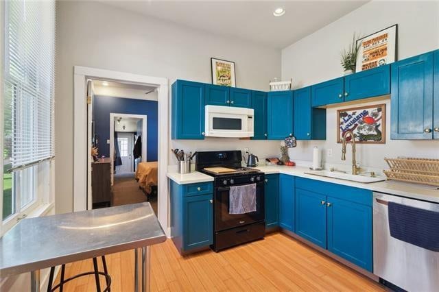 kitchen featuring blue cabinetry, dishwasher, black range with electric stovetop, and light wood-type flooring