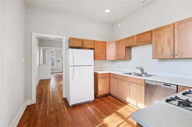 kitchen with white appliances, hardwood / wood-style flooring, and sink