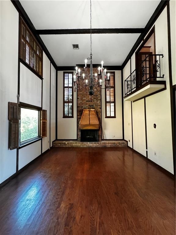 unfurnished living room featuring a brick fireplace, wood-type flooring, and a chandelier