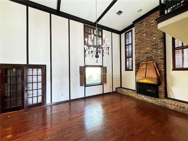 unfurnished living room featuring an inviting chandelier, a brick fireplace, a wall of windows, and hardwood / wood-style flooring