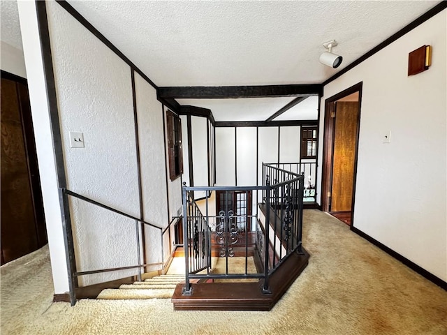 stairs featuring beamed ceiling, a textured ceiling, and carpet