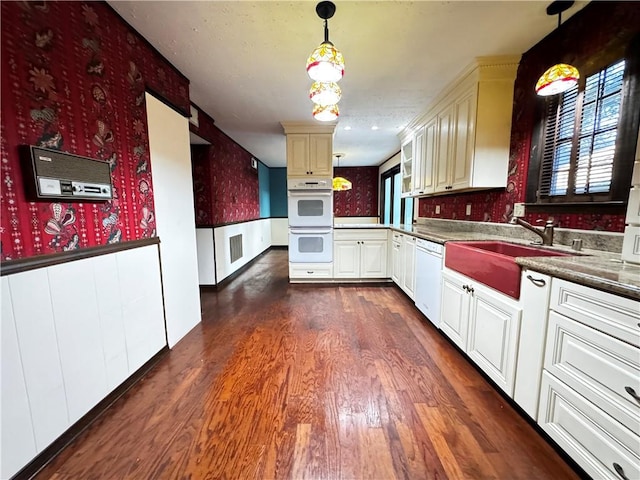 kitchen with pendant lighting, white appliances, sink, and dark hardwood / wood-style flooring