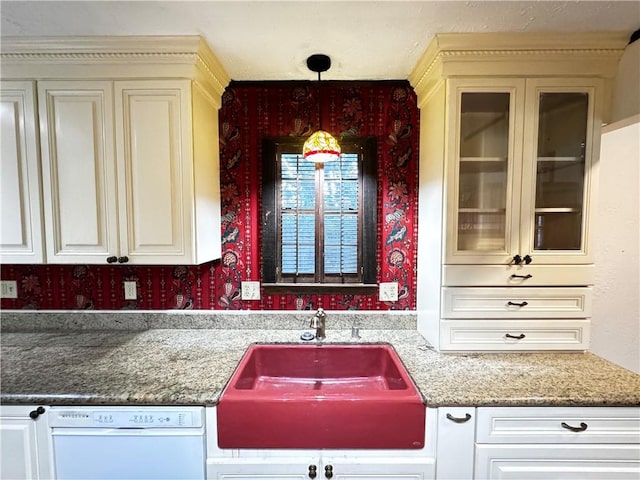 kitchen with dark stone countertops, pendant lighting, white dishwasher, and sink