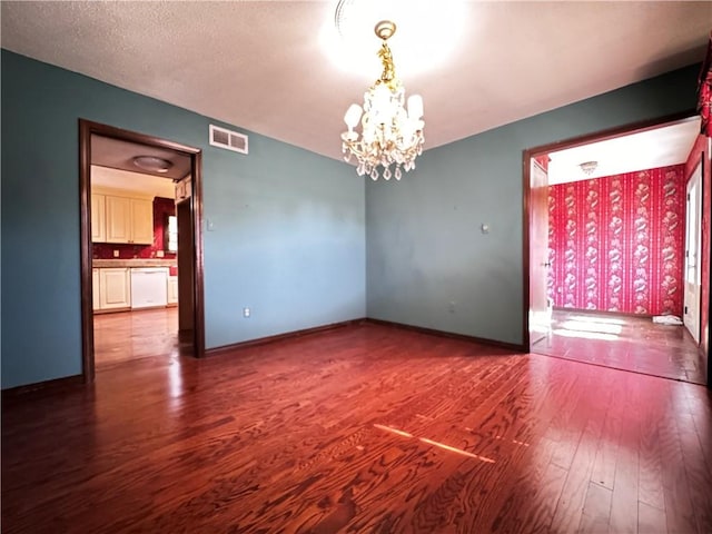 spare room featuring a chandelier, a textured ceiling, and hardwood / wood-style flooring