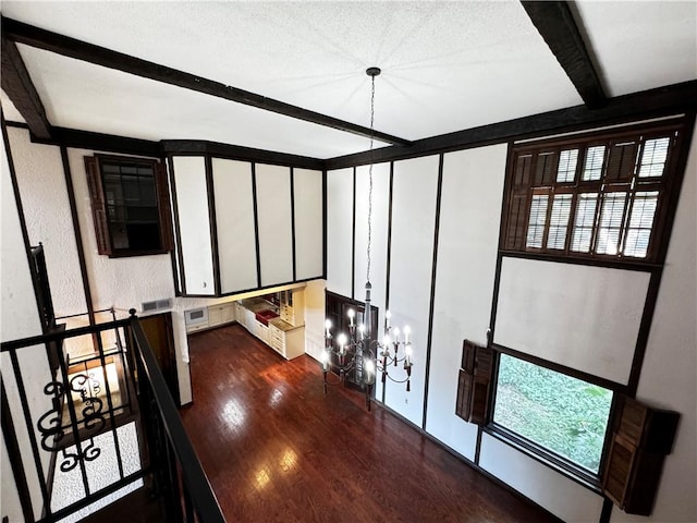 hallway featuring an inviting chandelier, dark hardwood / wood-style floors, and beam ceiling