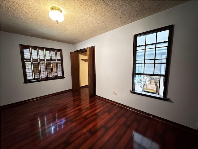 spare room featuring a textured ceiling and dark hardwood / wood-style floors