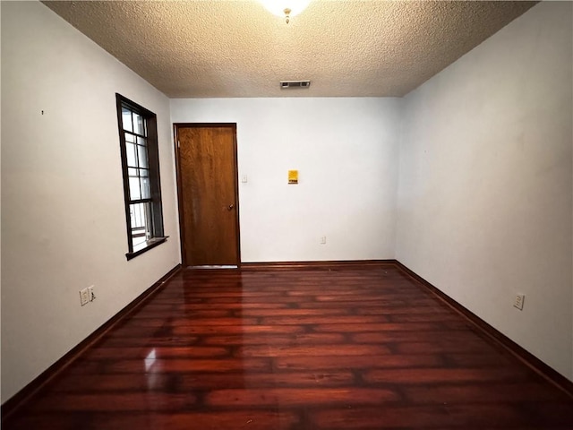 unfurnished room featuring a textured ceiling and dark wood-type flooring