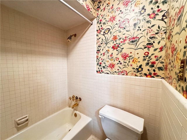 bathroom featuring tiled shower / bath combo, tile walls, and toilet