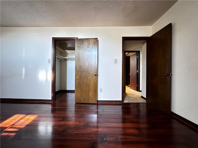 unfurnished bedroom featuring a textured ceiling and dark hardwood / wood-style floors