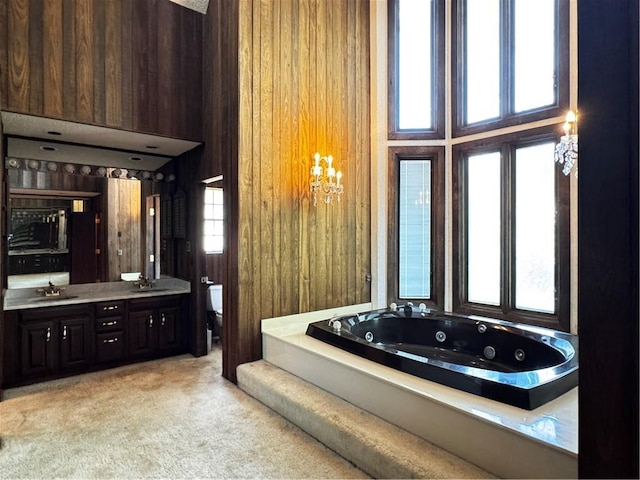 bathroom featuring a tub to relax in, wooden walls, vanity, and toilet