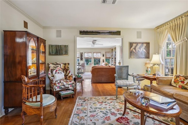 living room featuring wood-type flooring, plenty of natural light, ornamental molding, and ceiling fan