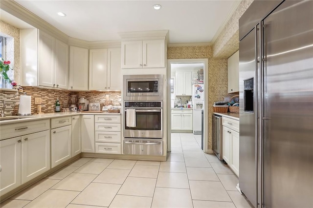 kitchen with white cabinetry, light tile patterned flooring, built in appliances, and crown molding