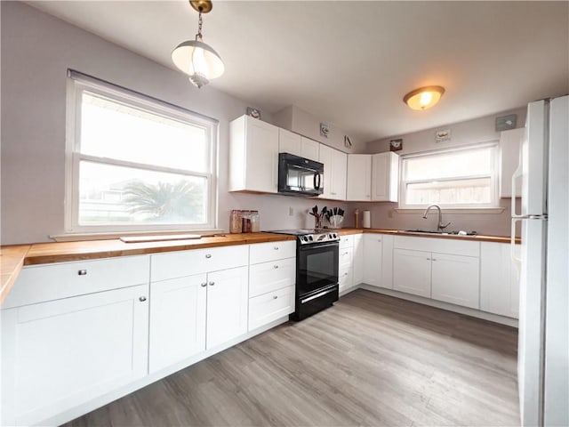 kitchen with black appliances, plenty of natural light, pendant lighting, and white cabinets