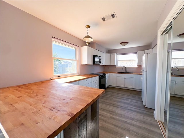 kitchen featuring black range with electric stovetop, white cabinetry, butcher block countertops, pendant lighting, and hardwood / wood-style flooring