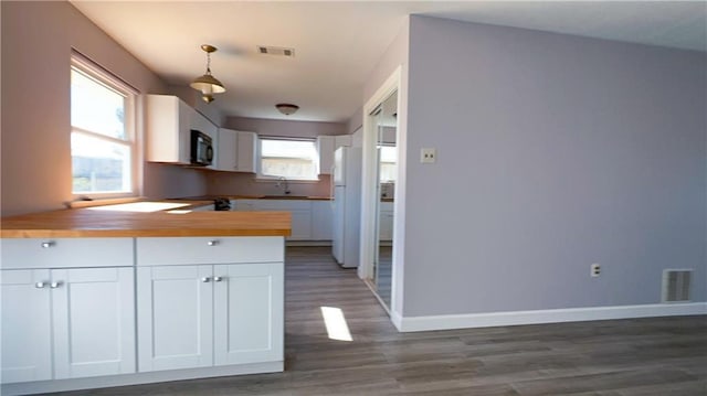 kitchen with pendant lighting, white cabinets, white refrigerator, dark hardwood / wood-style floors, and butcher block counters