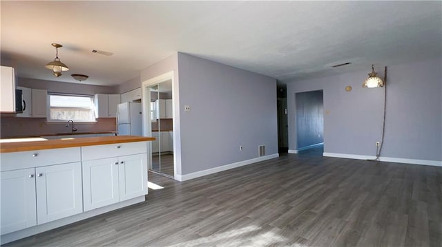 kitchen featuring dark hardwood / wood-style flooring, white refrigerator, decorative light fixtures, butcher block countertops, and white cabinetry