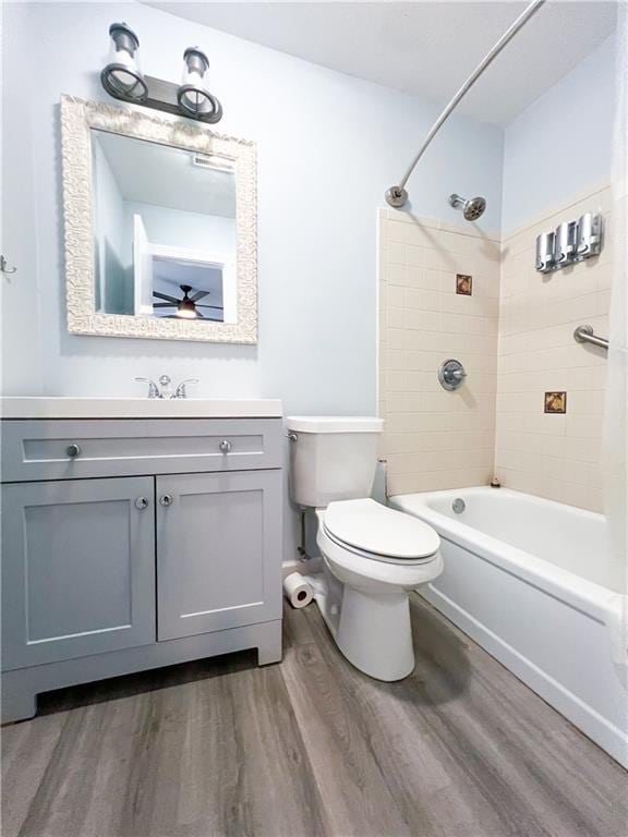 full bathroom featuring hardwood / wood-style floors, vanity, tiled shower / bath, ceiling fan, and toilet