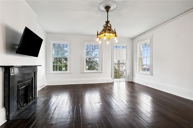 unfurnished living room featuring an inviting chandelier and dark wood-type flooring