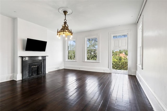 unfurnished living room featuring an inviting chandelier and dark hardwood / wood-style floors