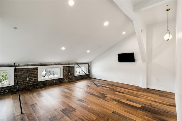 unfurnished living room with vaulted ceiling, brick wall, a healthy amount of sunlight, and dark hardwood / wood-style flooring