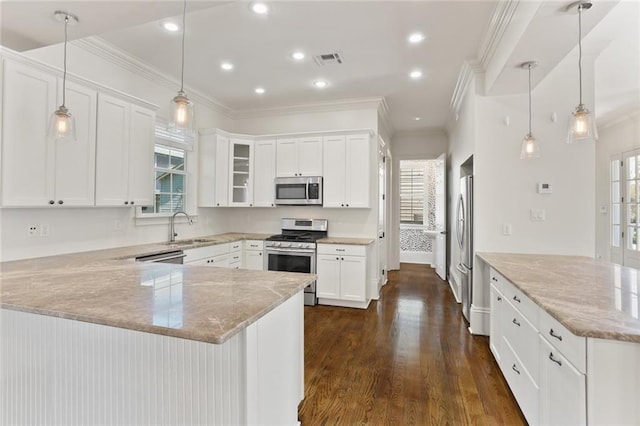 kitchen with a wealth of natural light, appliances with stainless steel finishes, hanging light fixtures, and white cabinetry