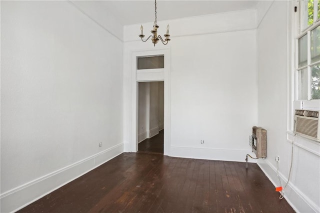 empty room featuring heating unit, dark hardwood / wood-style flooring, and a chandelier