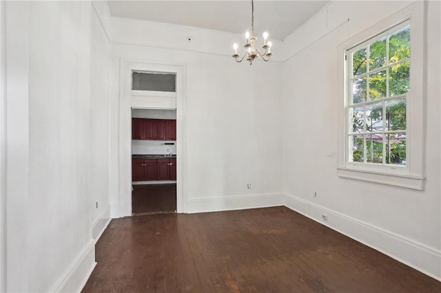 empty room featuring dark hardwood / wood-style flooring and a notable chandelier