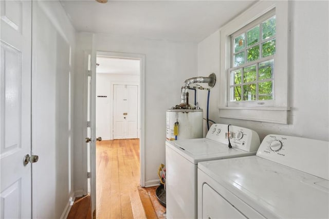 washroom with light wood-type flooring, washer and clothes dryer, and water heater