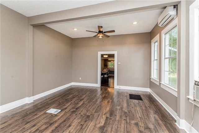 empty room featuring ceiling fan, dark hardwood / wood-style floors, a wall mounted air conditioner, and a wealth of natural light