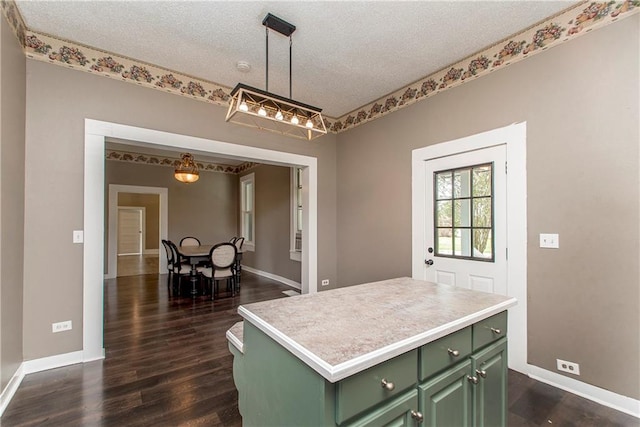 kitchen with hanging light fixtures, a kitchen island, green cabinetry, a textured ceiling, and dark wood-type flooring