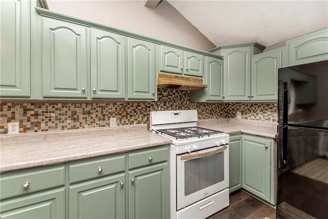 kitchen featuring lofted ceiling, white gas range, black refrigerator, and tasteful backsplash