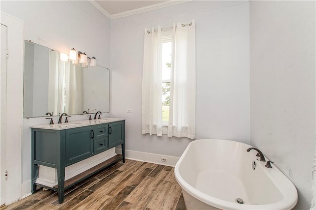 bathroom featuring ornamental molding, hardwood / wood-style floors, vanity, and a bathing tub