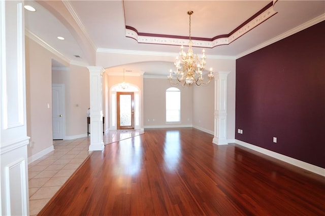 unfurnished room with ornamental molding, a chandelier, light hardwood / wood-style flooring, and ornate columns