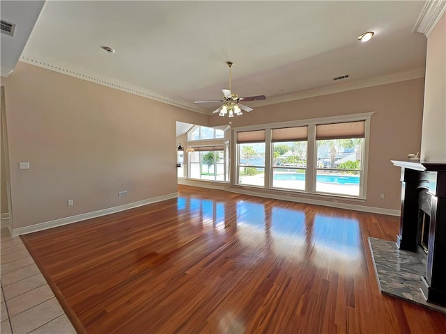 unfurnished living room featuring crown molding, ceiling fan, wood-type flooring, and a wealth of natural light