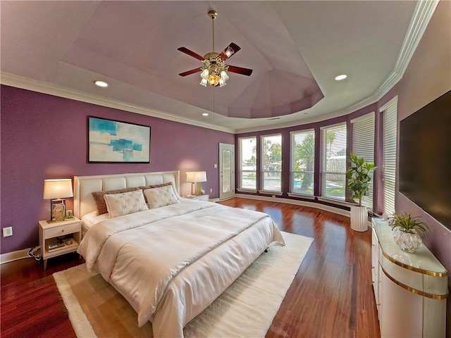 bedroom with ceiling fan, a tray ceiling, dark hardwood / wood-style flooring, and crown molding