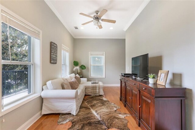 living room featuring crown molding, light hardwood / wood-style floors, ceiling fan, and a wealth of natural light