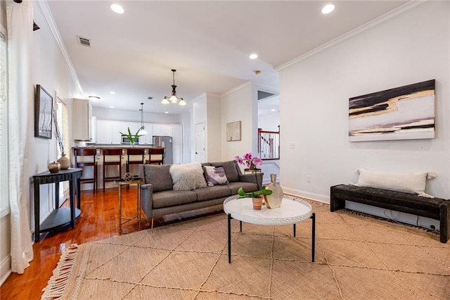 living room with a notable chandelier, hardwood / wood-style flooring, and ornamental molding